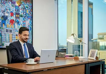 A professional works confidently from a private Servcorp office in Saudi Arabia, enjoying premium workspace design with skyline views and cultural flair.