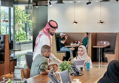 Professionals collaborate in a vibrant coworking space at Servcorp Al Faisaliah Center, blending Saudi elegance with world-class business amenities.